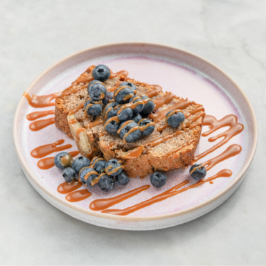 Banana Bread Eine Scheibe hausgemachtes Banana Bread mit Blaubeeren und Sirup